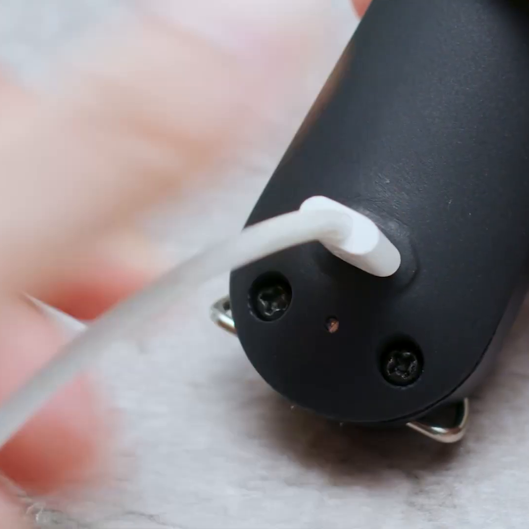A white USB Type-C cable plugged into the charging port on the underside of the ZAPPER+ handle